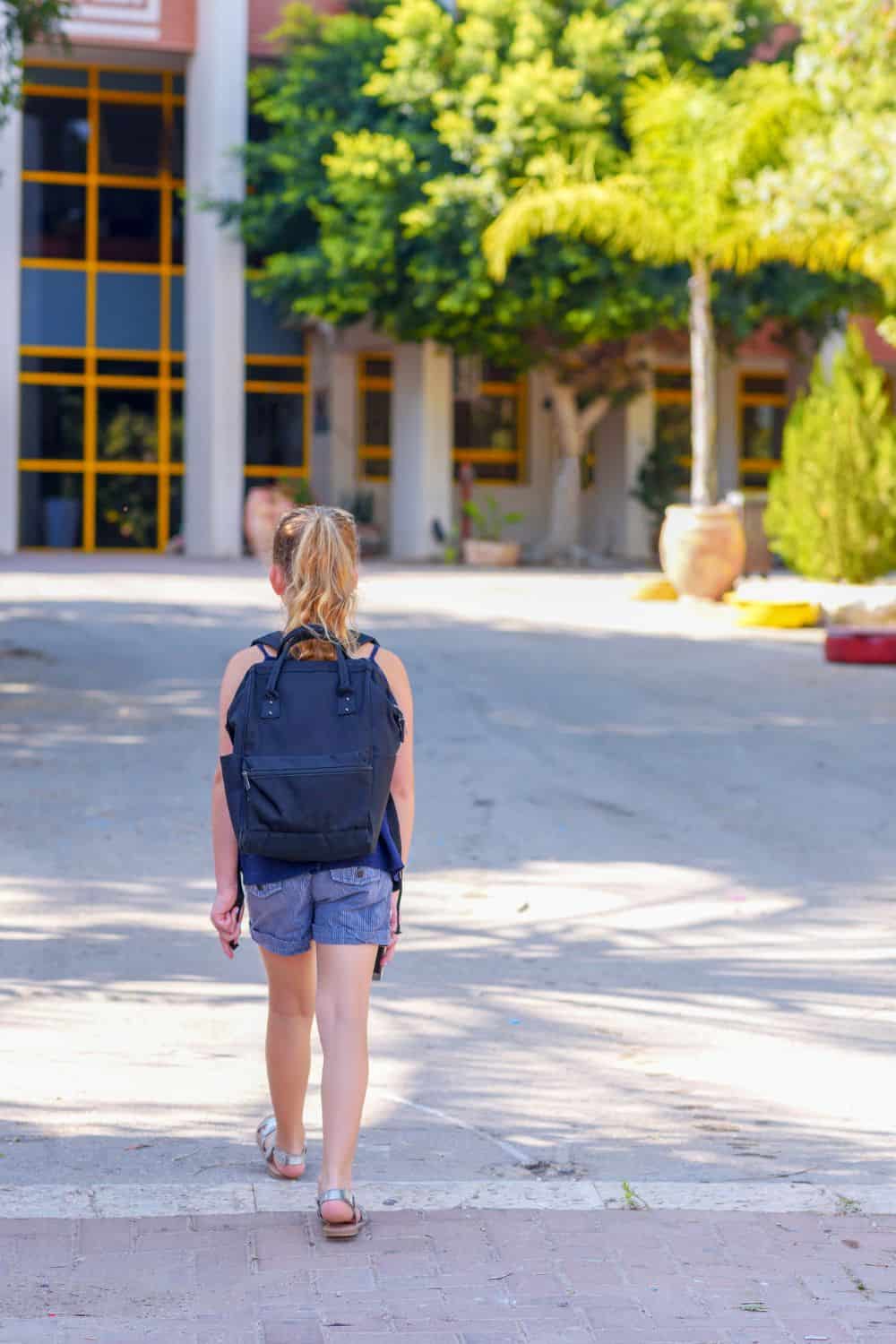 Teenage girl walking into school ground.