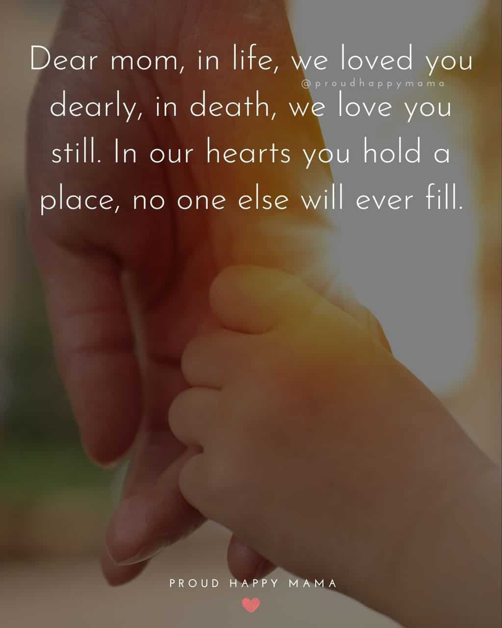 Child holding mother's pinky finger with text overlay, ‘Dear mom, in life, we loved you dearly, in death, we love you still. In our hearts you hold a place, no one else will ever fill.’