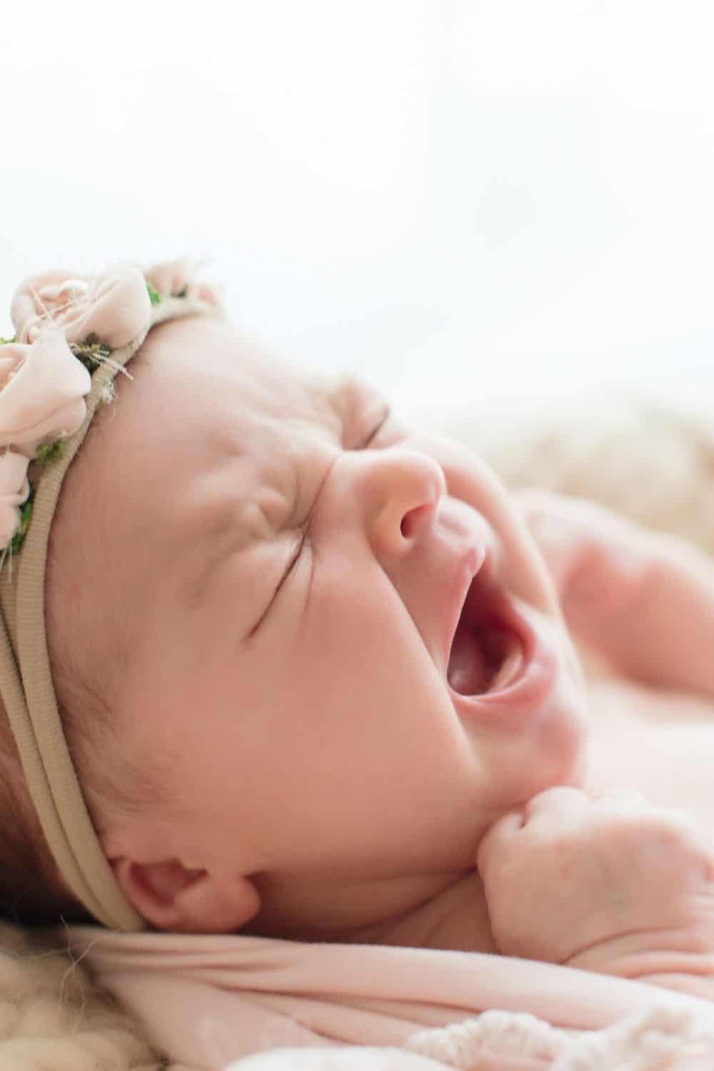 Baby with headband yawning.