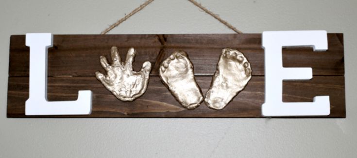Handmade wooden keepsake sign that says love with hand and foot prints.