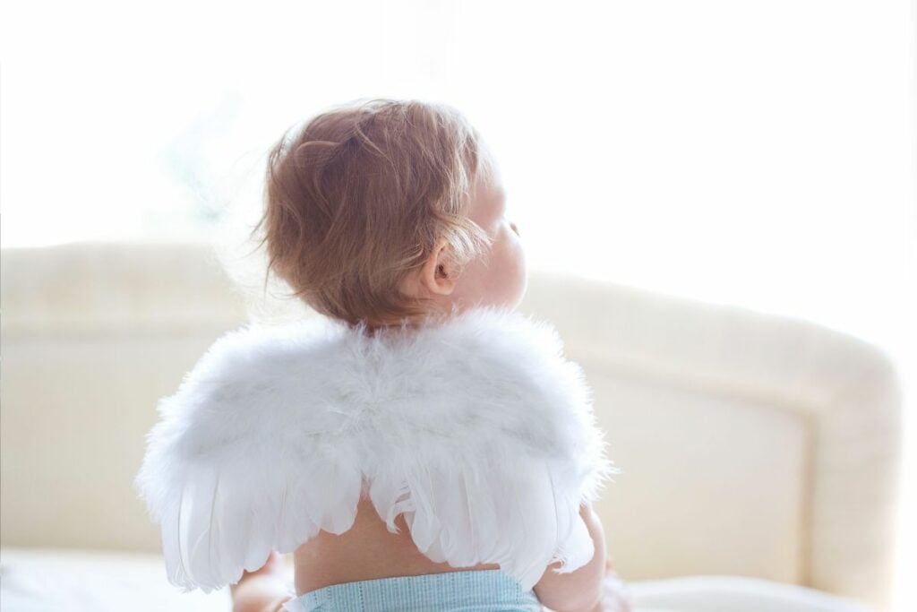 Baby boy with angel wings with back to camera.