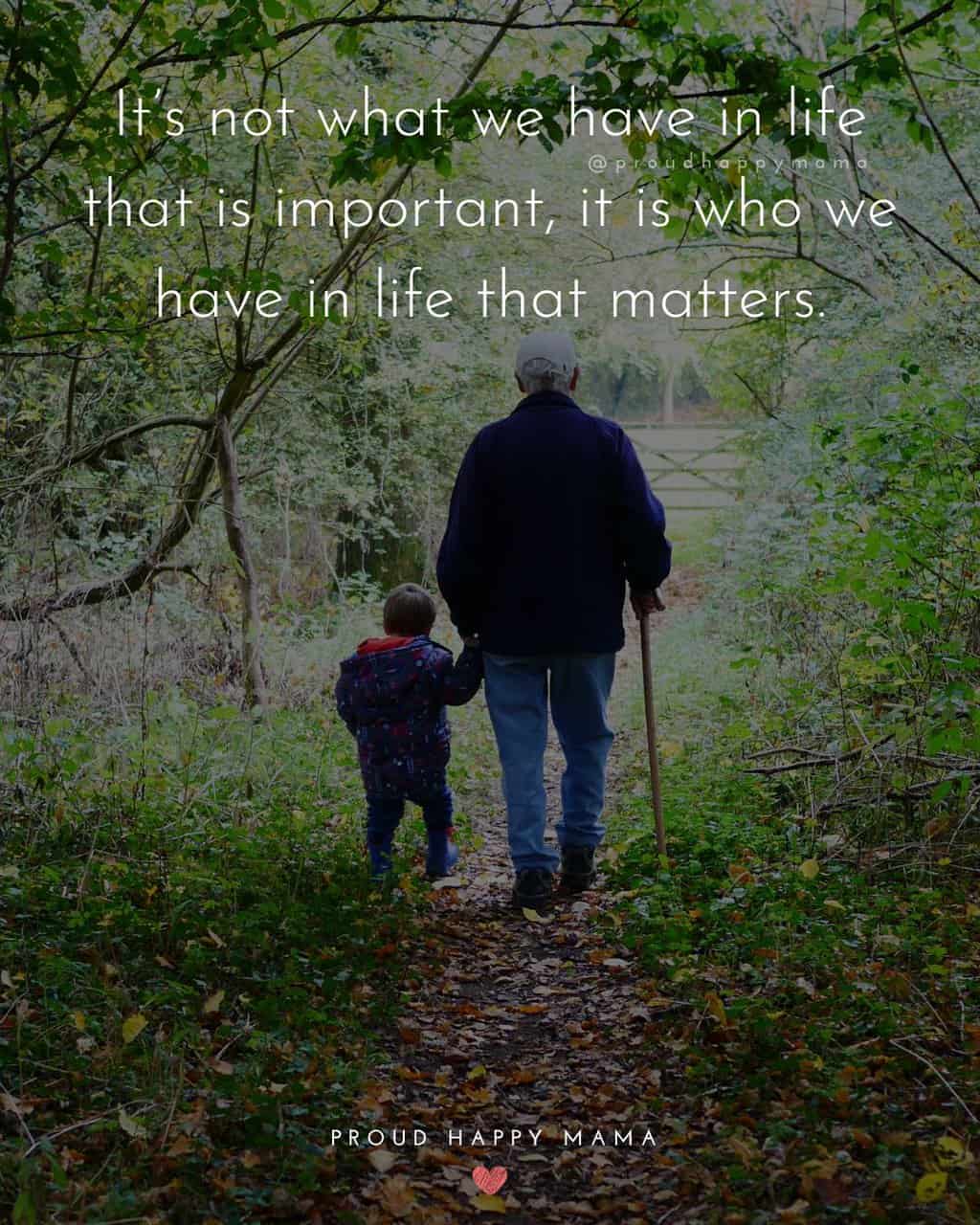 Grandfather walking with grandson in field with grandkids quote text overlay. ‘It’s not what we have in life that is important, it is who we have in life that matters.’