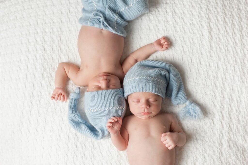 Twin baby boys in blue hats with unique boy names.